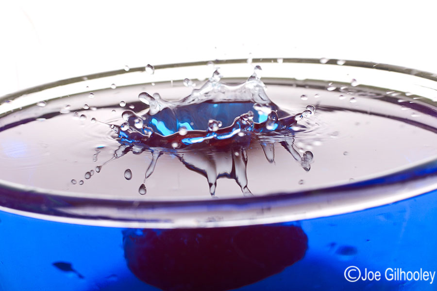 Dropping Water Droplets into coloured water in glass bowl