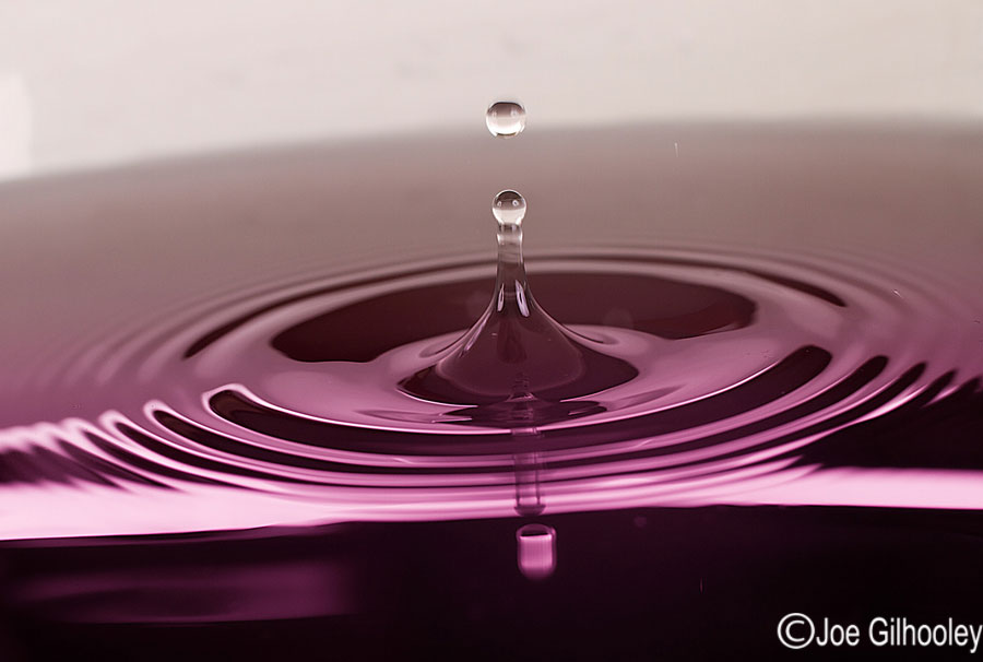 Dropping Water Droplets into coloured water in glass bowl