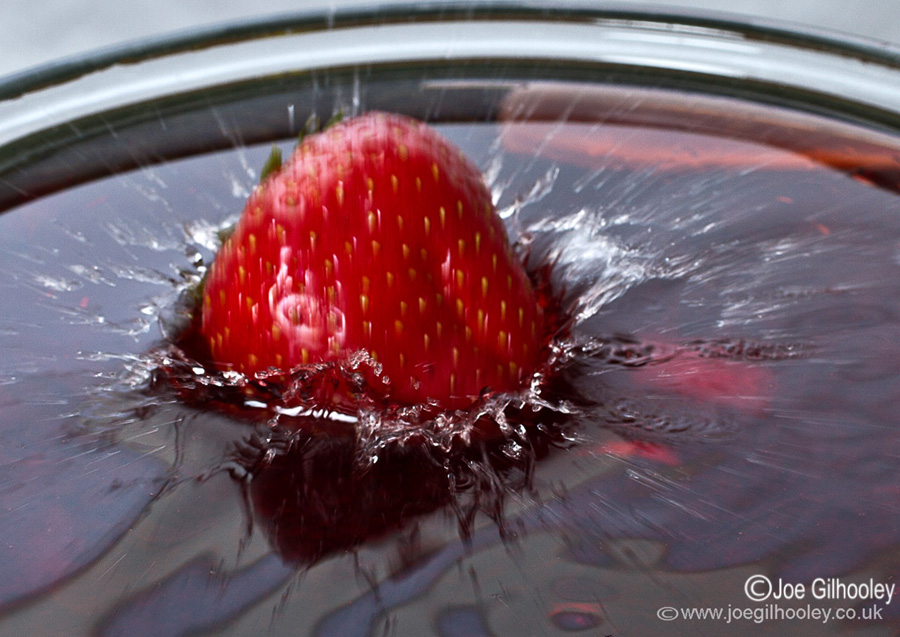 Strawberry falling into coloured water
