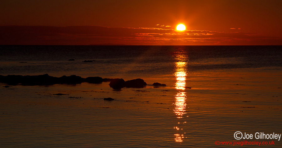 Sunrise at Yellowcraigs Beach. Sun breaking horizon and reflections starting.