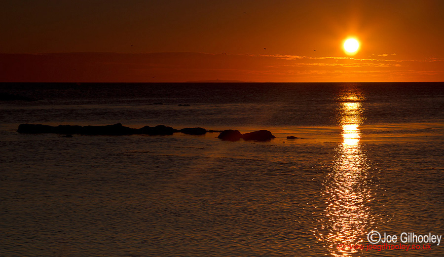 Sunrise at Yellowcraigs Beach. Sun breaking horizon and reflections starting.